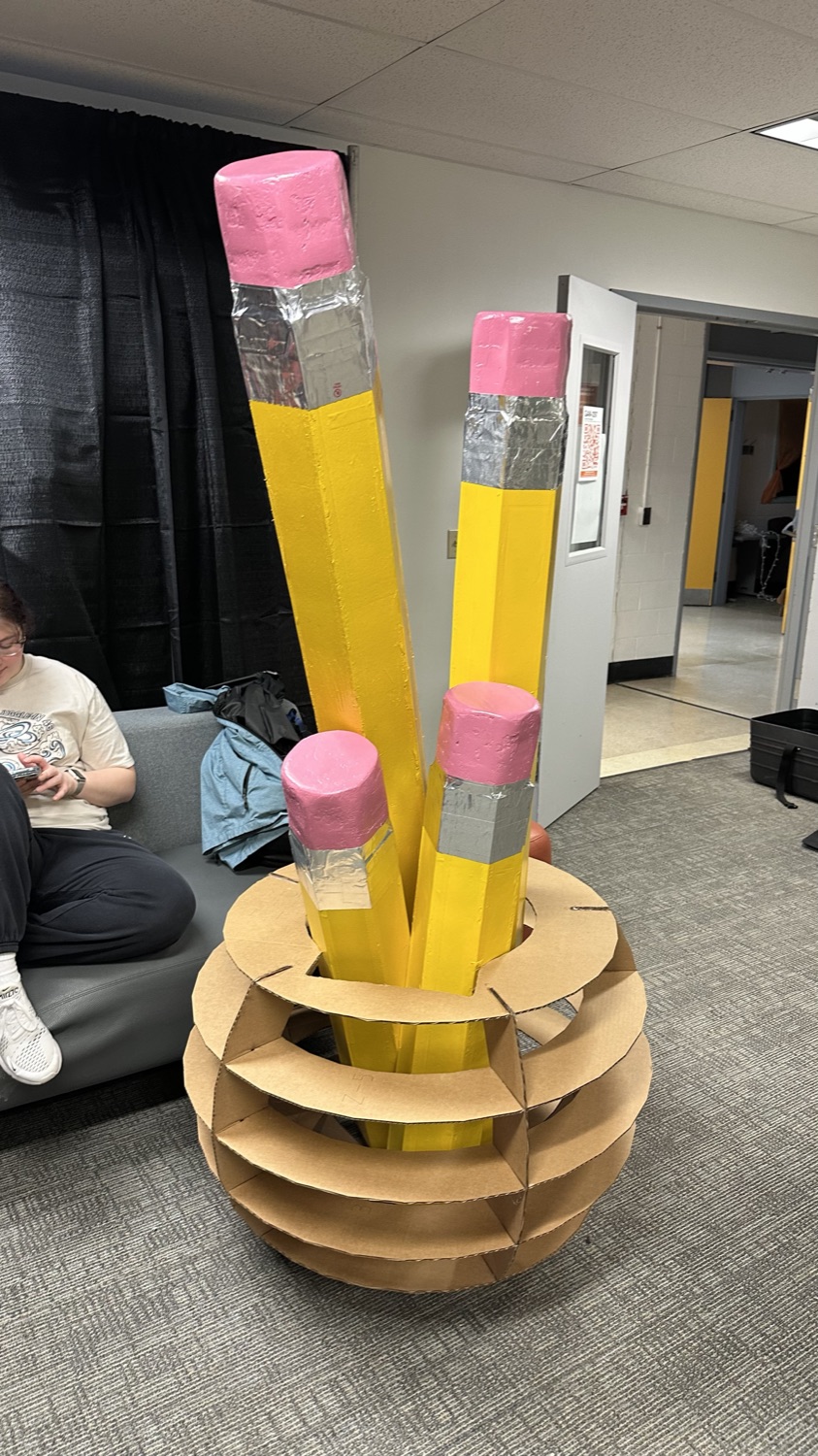 The full-size pencil props standing in a cardboard holder